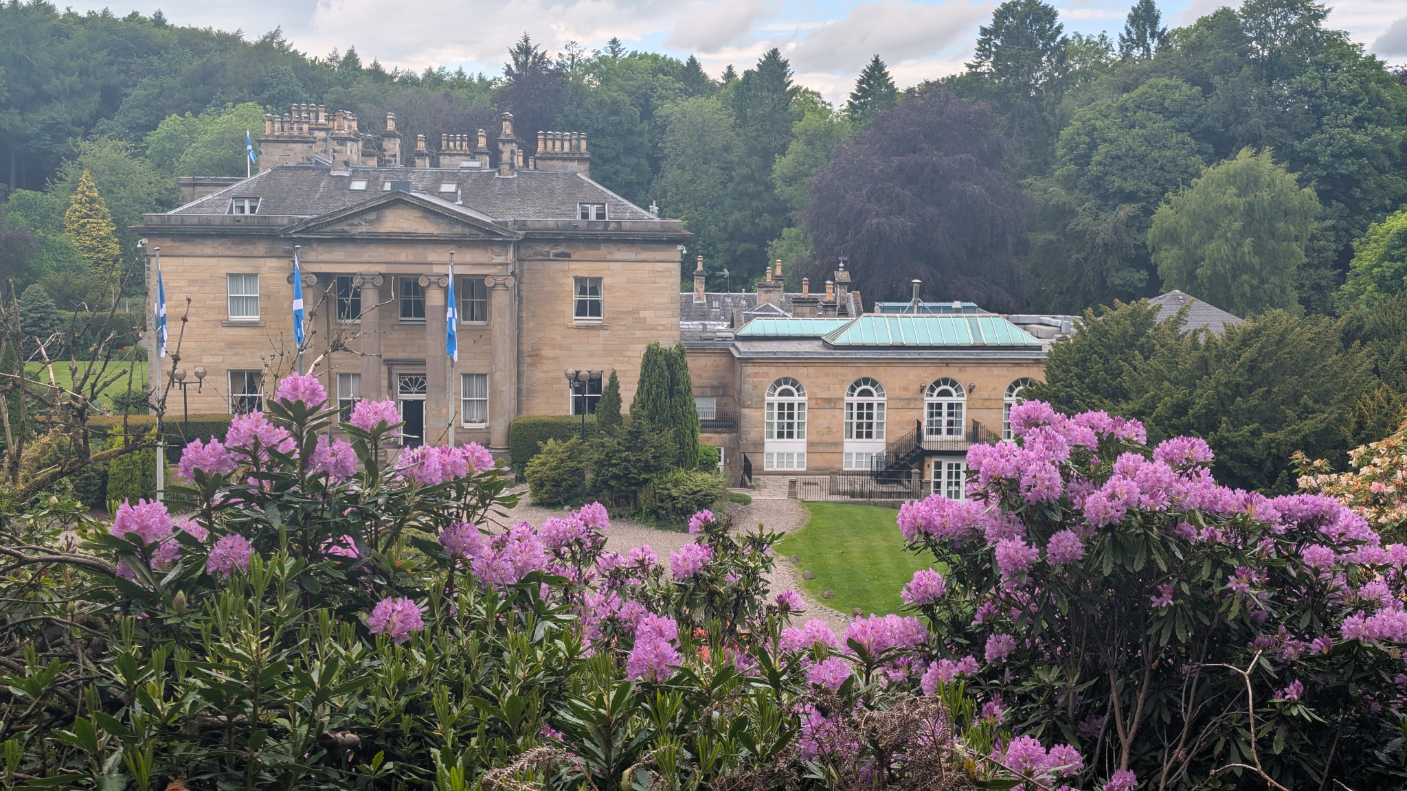 Historic manor house with blooming rhododendrons in Scotland